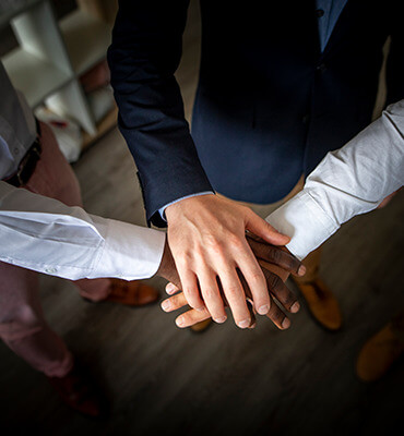 Stock overhead image of people stacking hands with one another signifying working together.