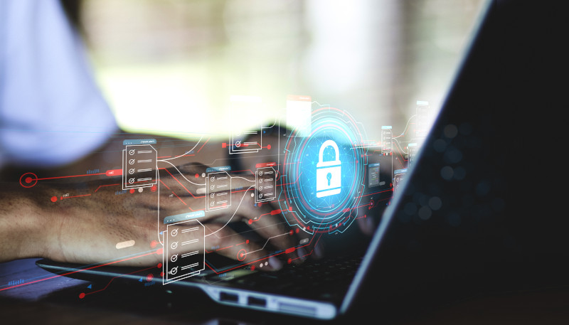 Close up of hands typing on laptop with graphic overlay of a padlock and other network-like elements.